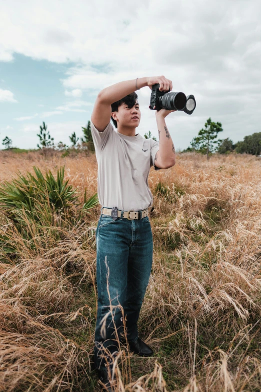 a man is holding a camera and standing in a field