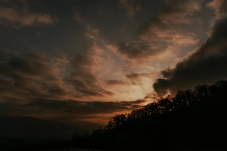 a cloudy sunset is pictured near trees