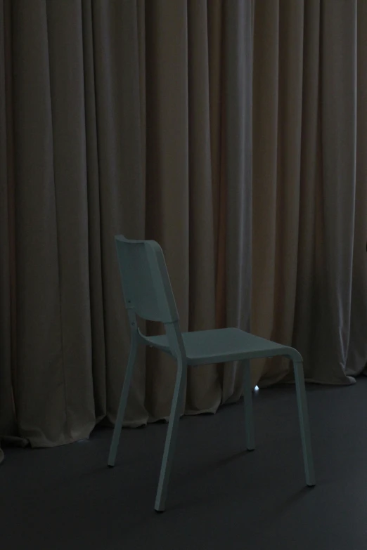 a white chair sitting on the floor near curtains