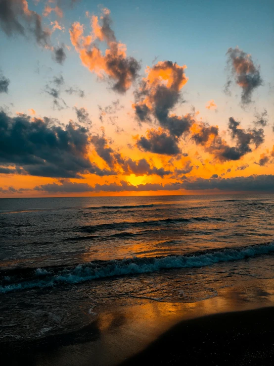 the sunset over the water with clouds in the sky