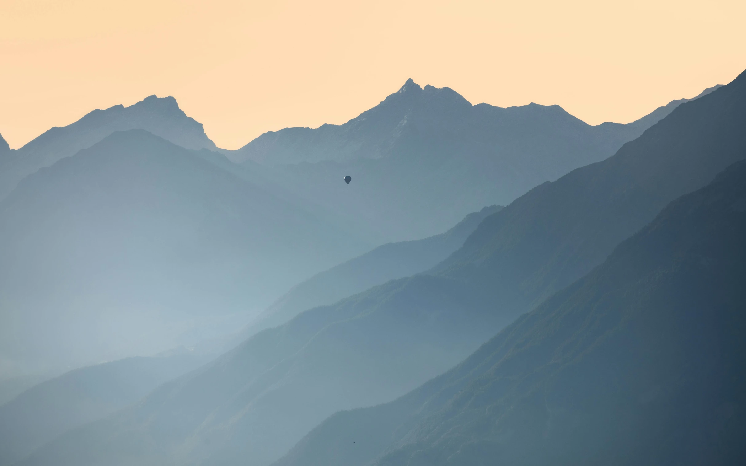 the view of mountains with a bird flying over them