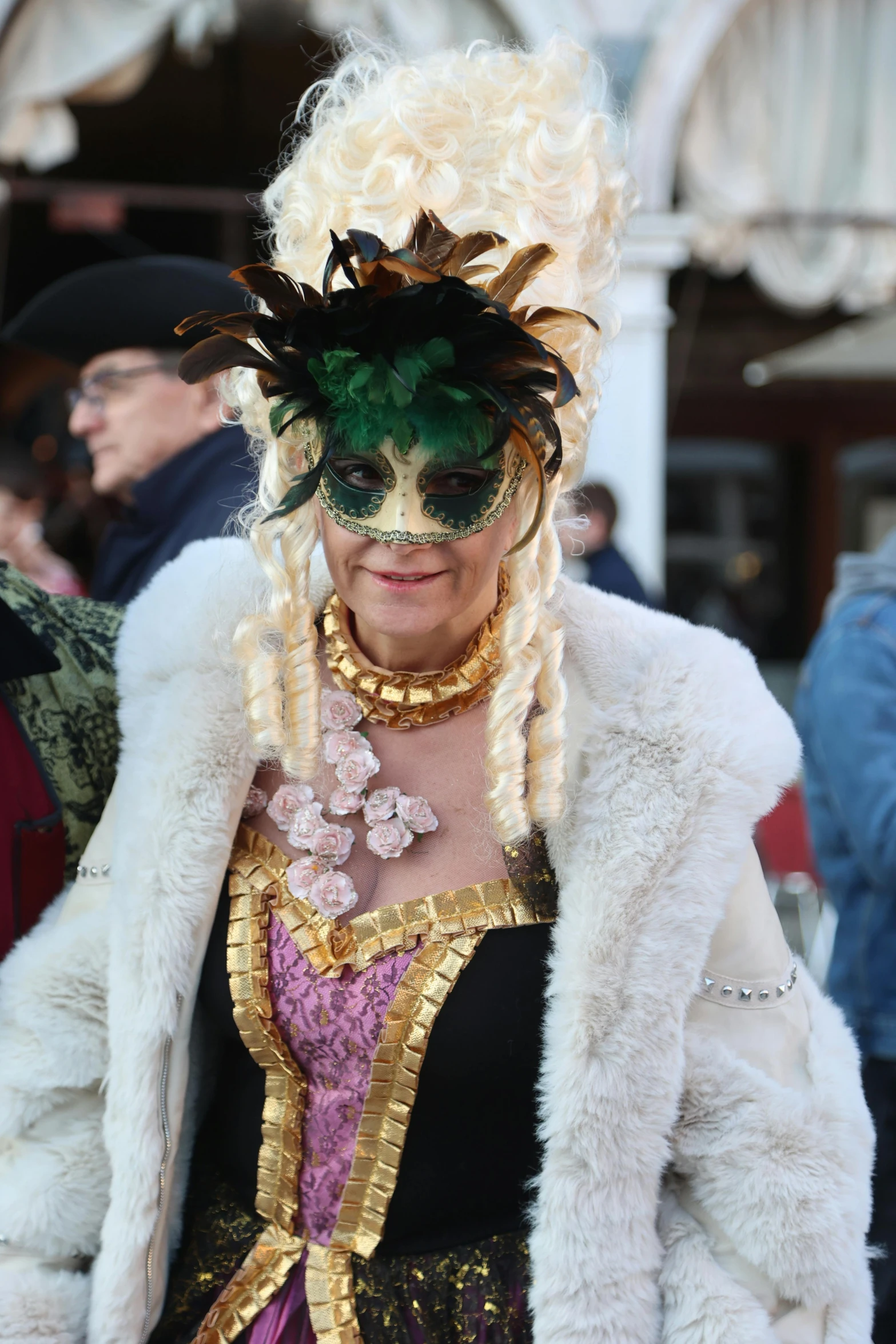 a woman wearing a white feathered costume and green mask