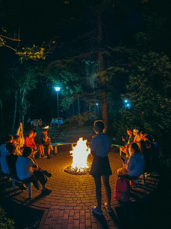 people are sitting around a fire at night