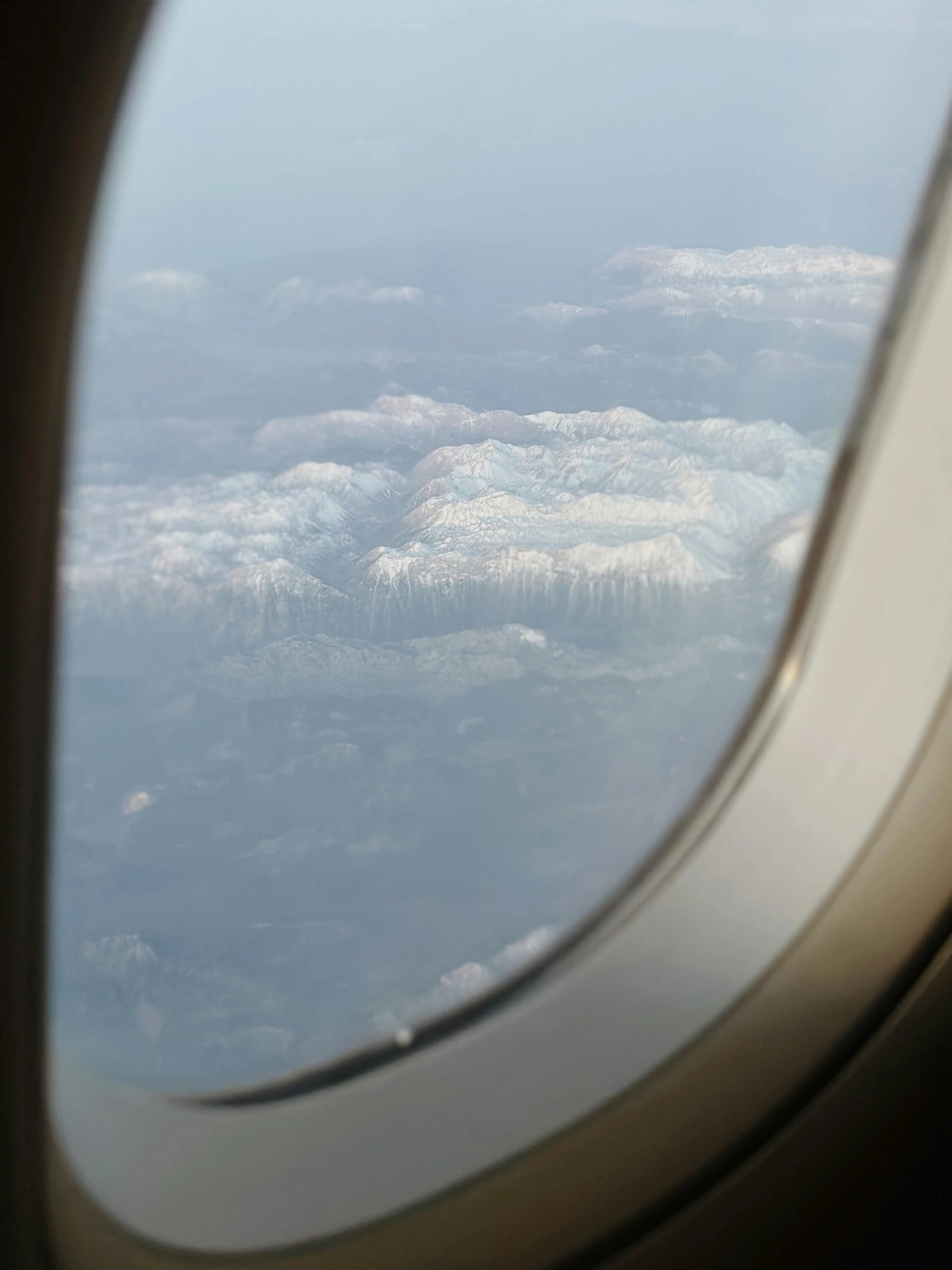 an airplane window looking down at some clouds and a lake