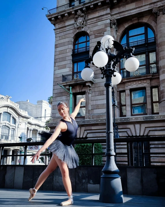 a woman posing near the lamppost with her hand in the air