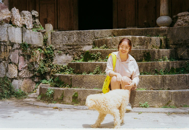 a lady with a dog standing outside on some steps