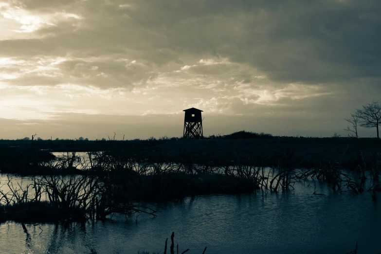 a tower stands on a hill near a lake