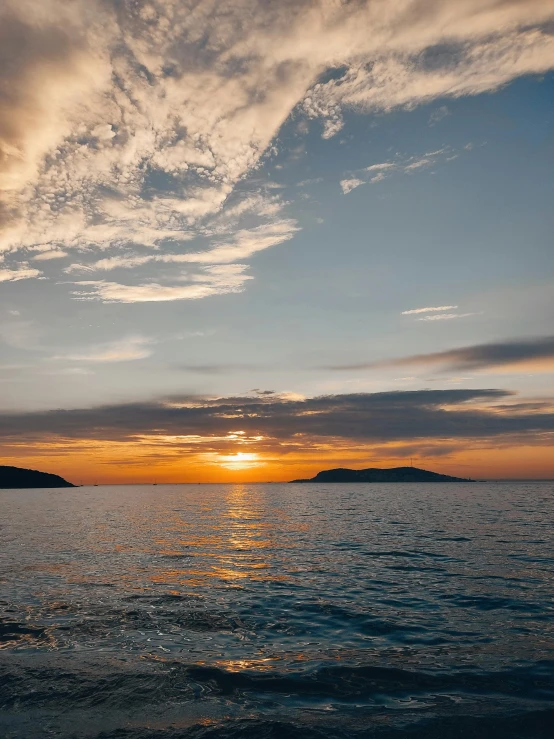 a boat sailing on the ocean during a sunset