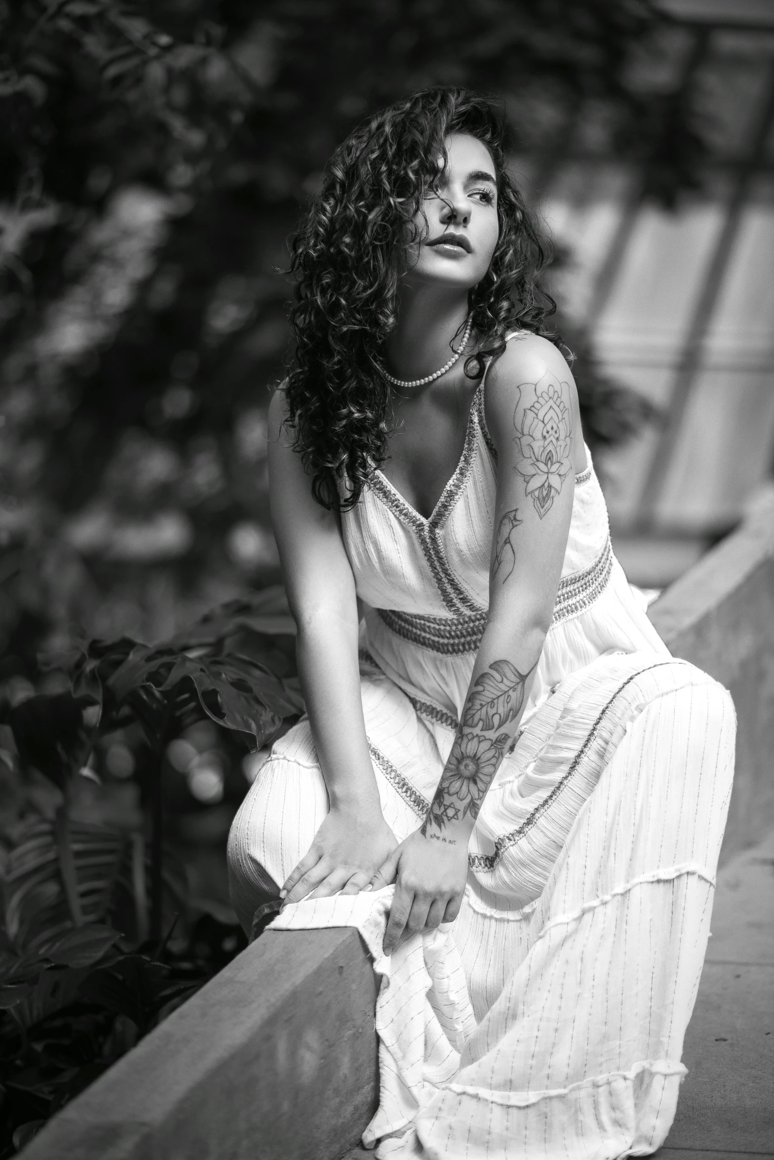 a woman posing in a long dress next to a bush