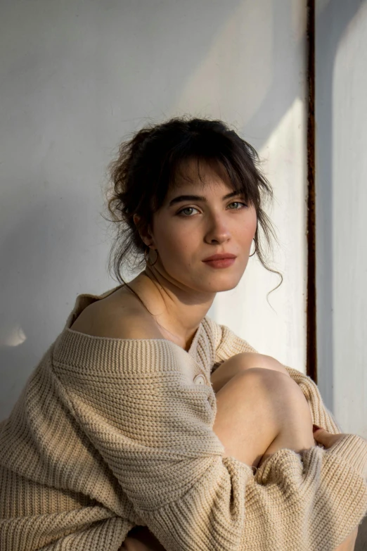 a young woman is sitting down outside by a wall