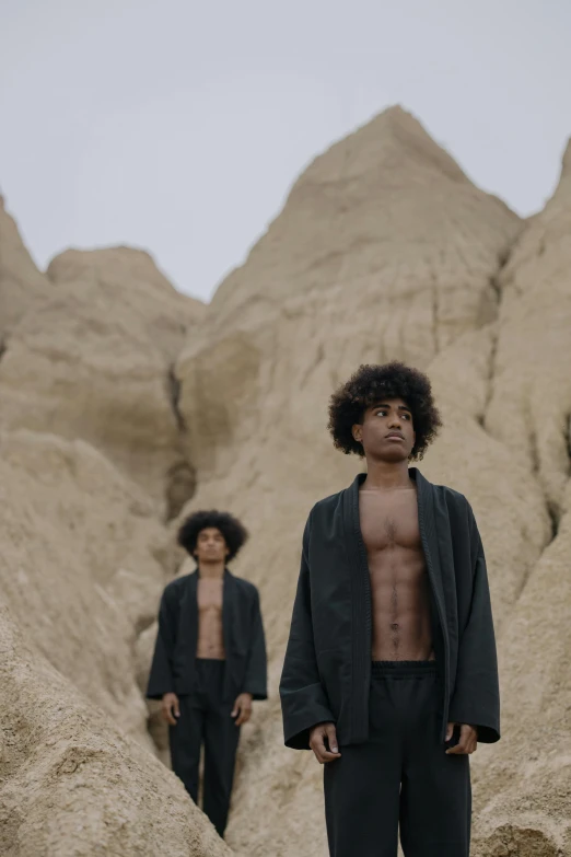 two men standing near some big rocks