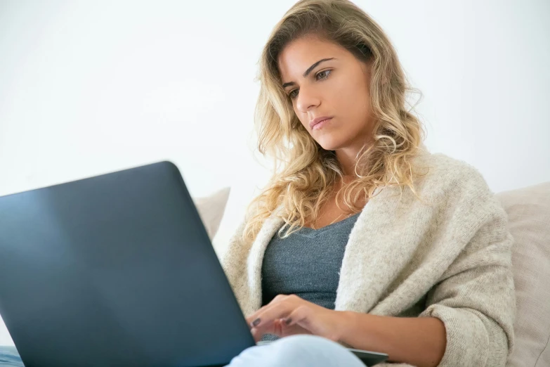 a young woman sitting on the couch using a laptop