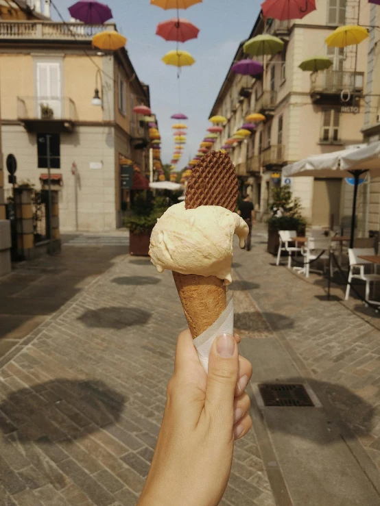 a person is holding up an ice cream cone with a cone shaped like an umbrella