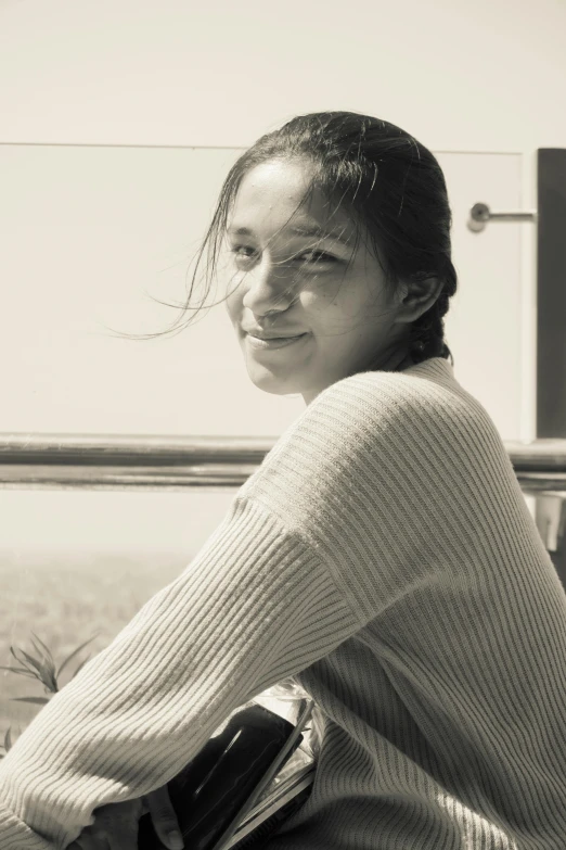 a woman sitting in front of a window smiling