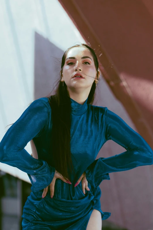 a woman posing in a dress in front of an artistic building