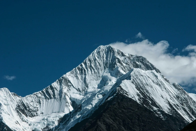 a very tall snowy mountain in the middle of a cloudy sky