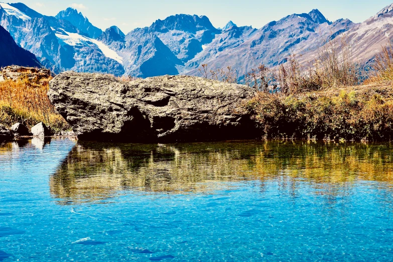 the blue water is reflecting rocks and mountains