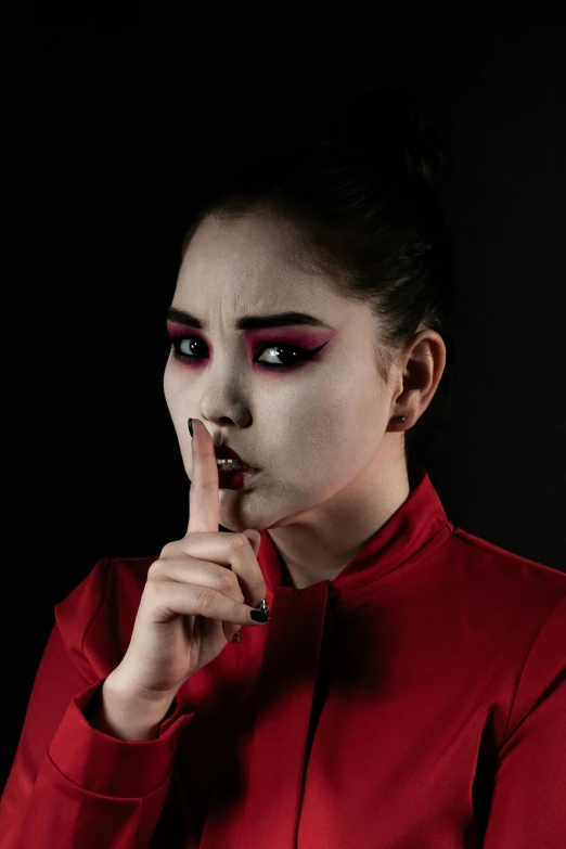 woman dressed as a geisha with red eyeshade pointing finger at camera