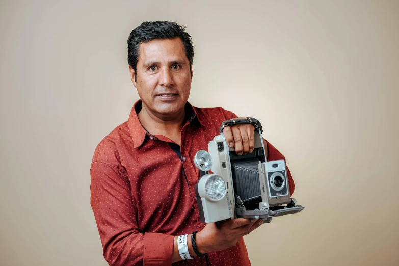 man in red shirt holding an old camera