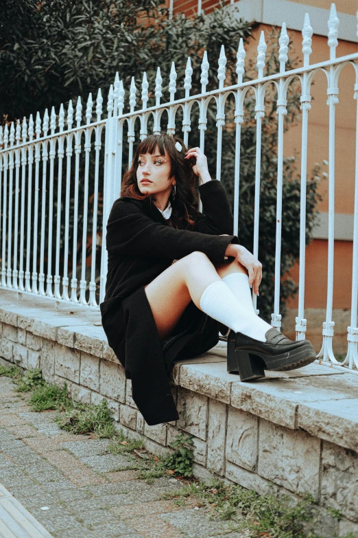 an attractive young woman posing with her legs crossed on some steps