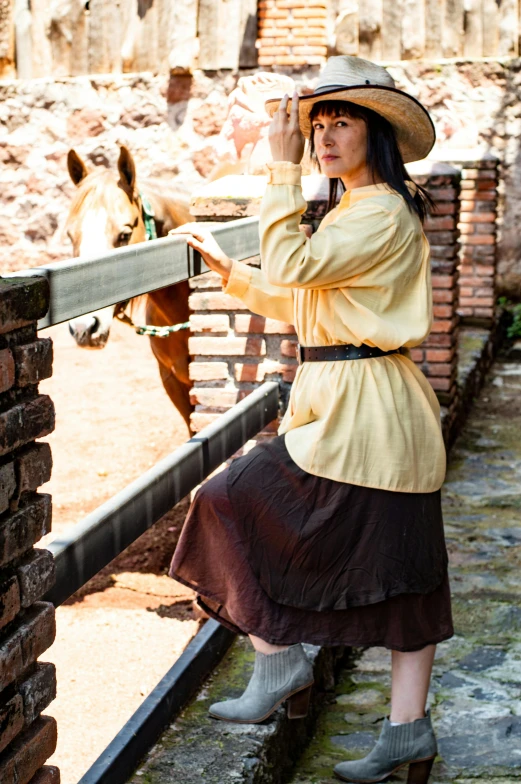 the woman is wearing a straw hat leaning over a fence