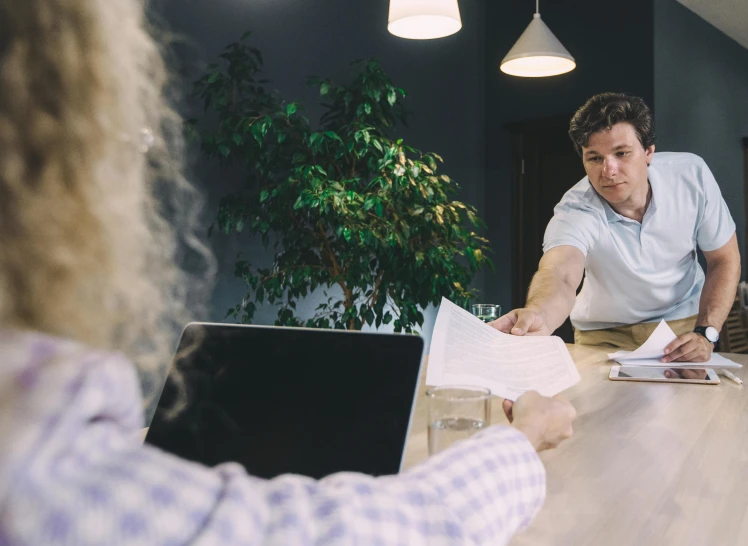 people sitting around a wooden table with papers