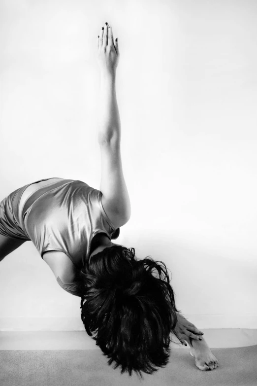 a woman in silver is upside down in an aerial pose