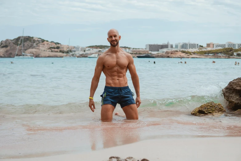 the man with  stands on the beach in his swimming trunks