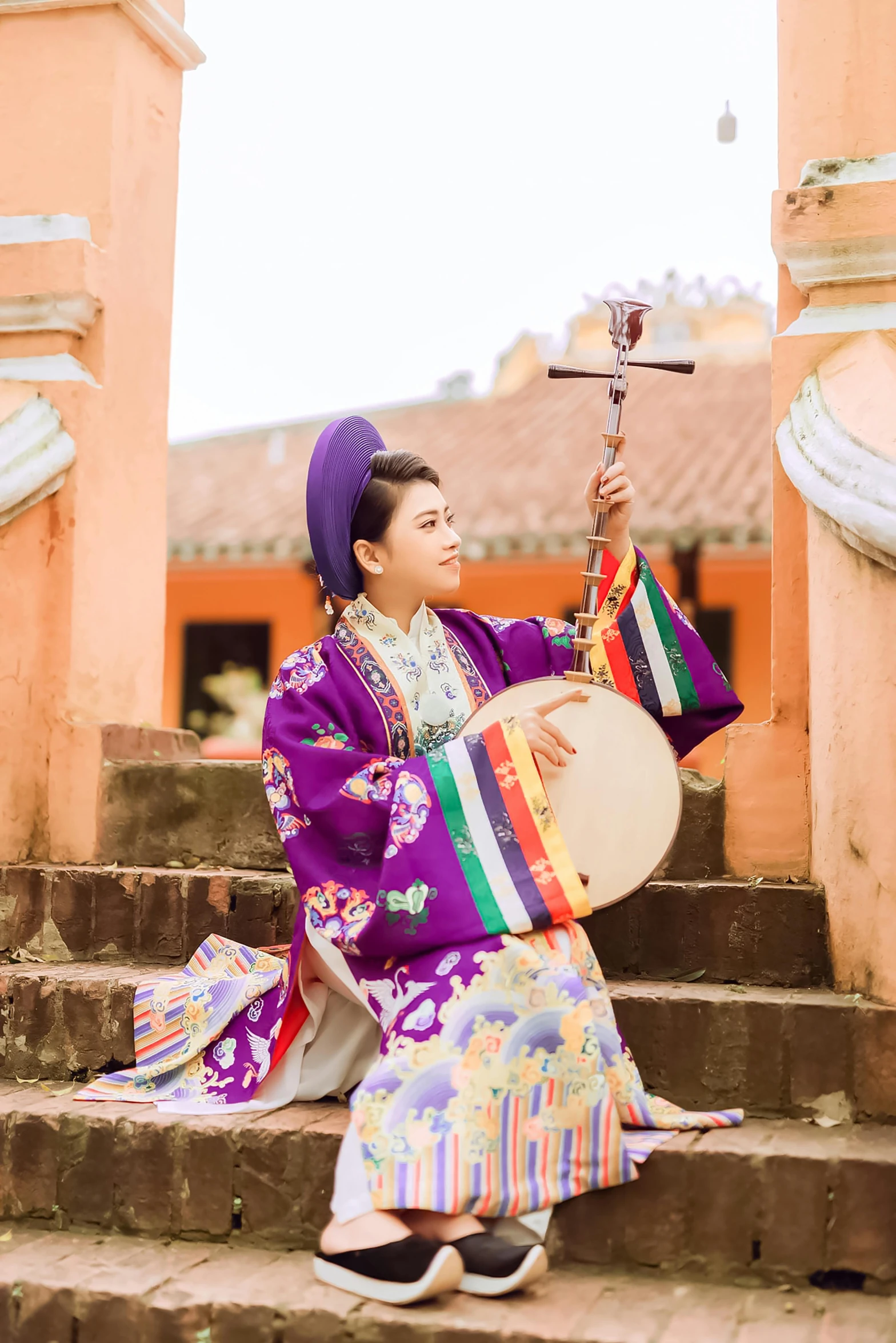 a young woman in a purple japanese kimono is playing a music instrument