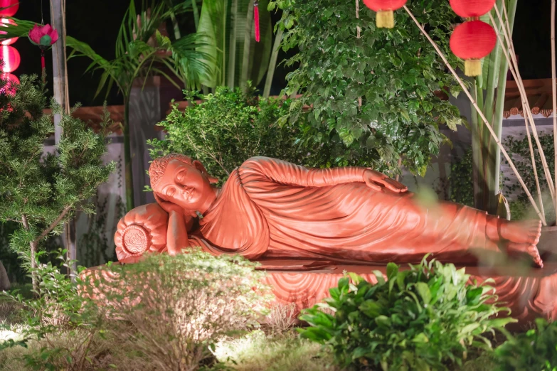 a small statue of buddha in a garden at night