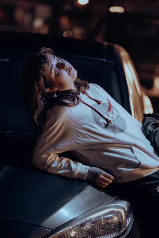 a woman laying on the hood of a car