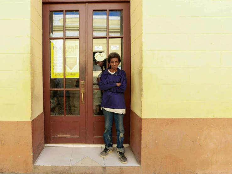 a young man standing in front of a brown door