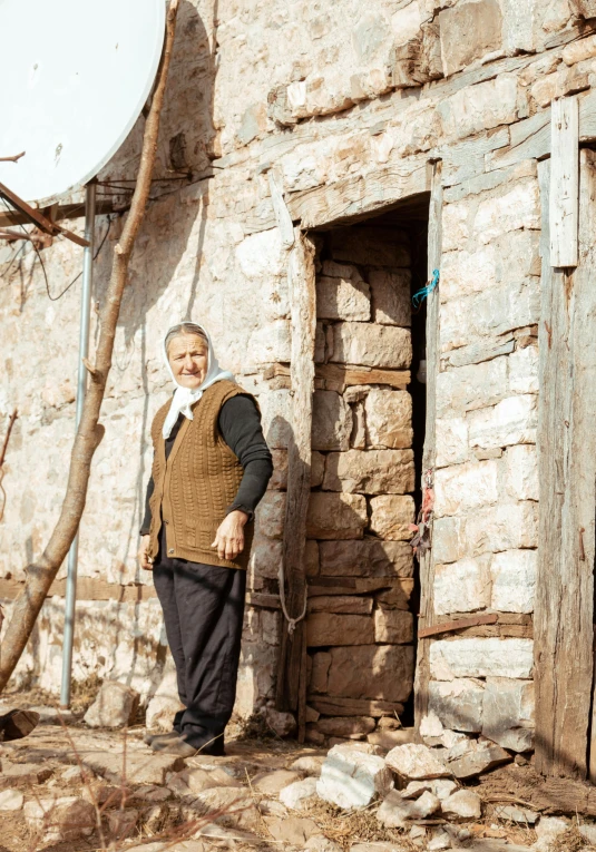 an old man poses by a building that is older than him