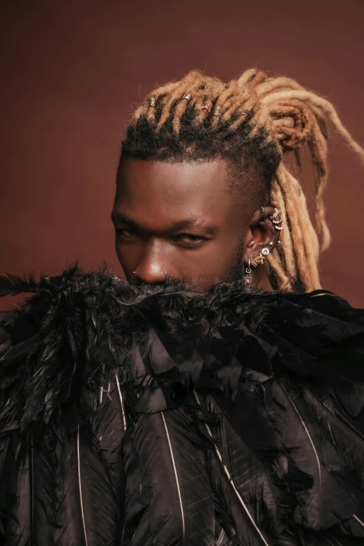 a man with dread locks wearing black feathers