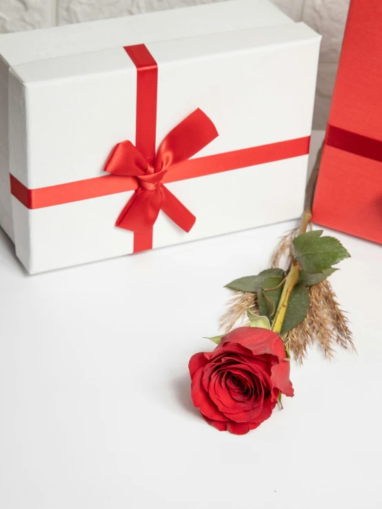 a rose and a white box with red bows