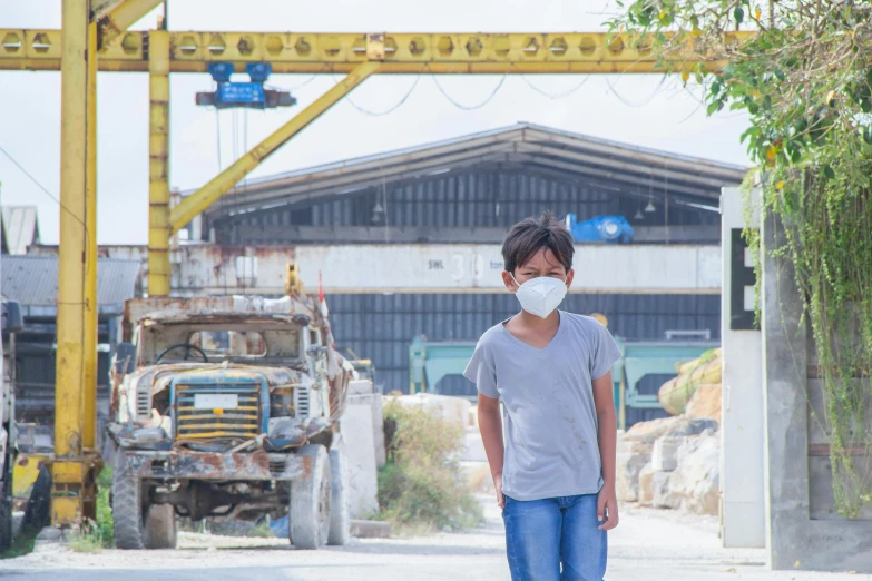 a boy with a face mask walks towards an old structure