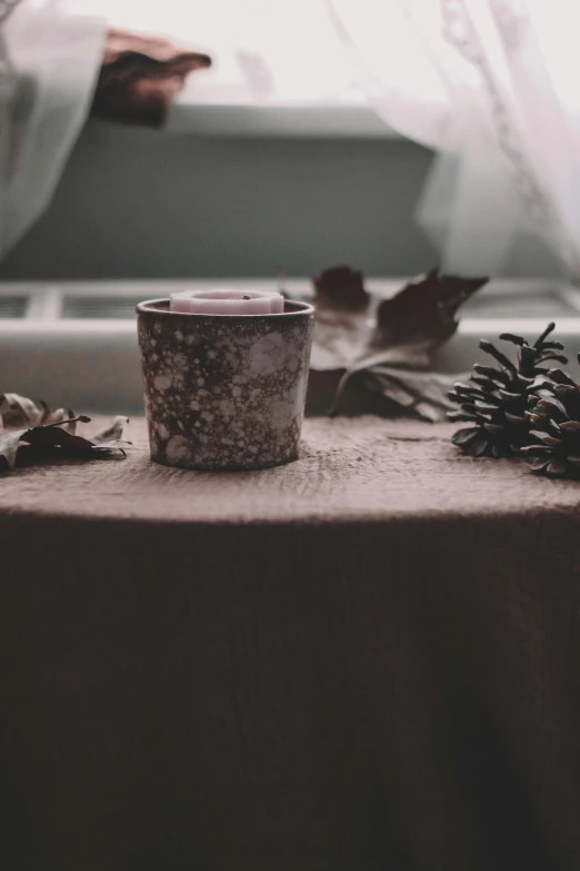 a cup and some leaves sitting on a table