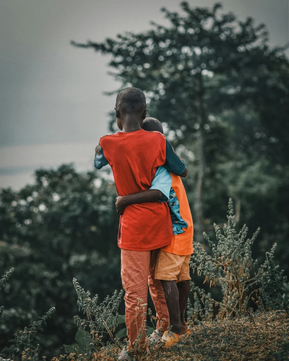 two children standing outside by a tree in the rain