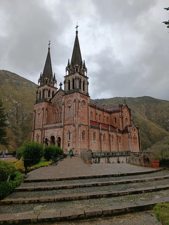 a stone building with three towers on a cloudy day