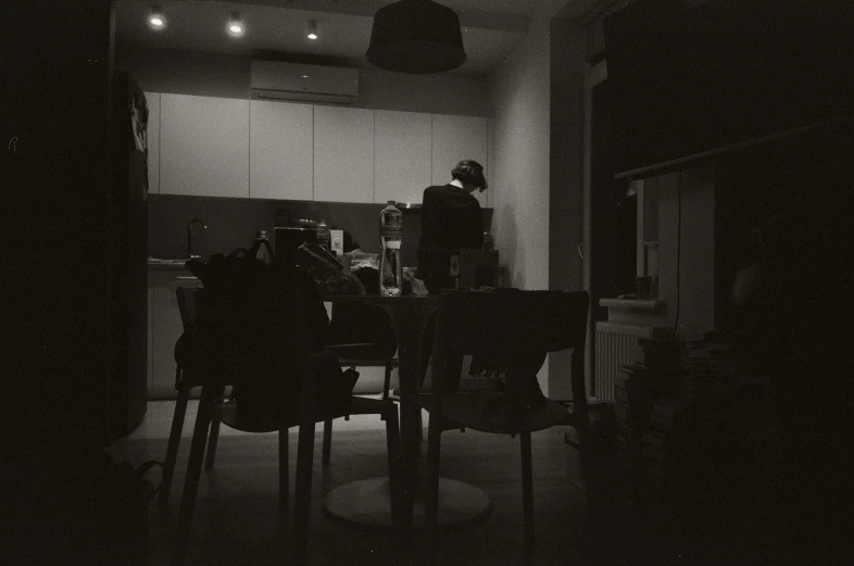 a person sitting in a dining room chair in a dark room