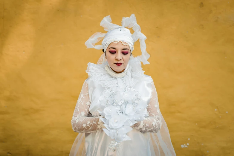 a lady that has a wedding gown and flower arrangement in hand