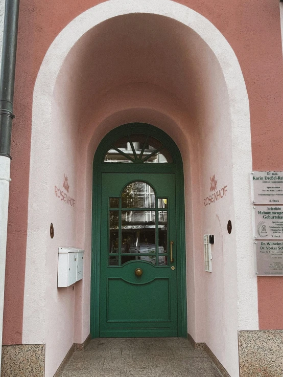 a green door on a pink building has words written on it