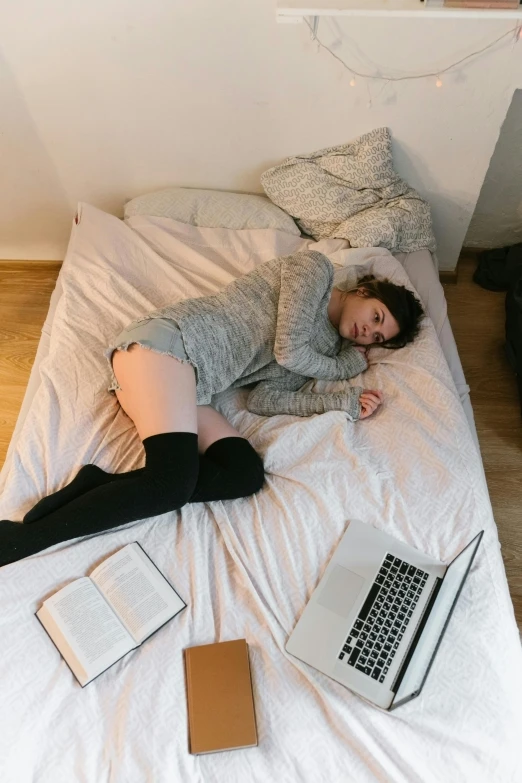 a woman laying in bed with three laptops