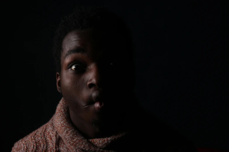 a dark man poses for a portrait while wearing a scarp