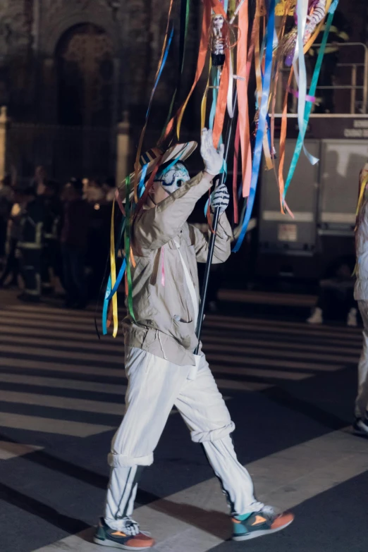 a man holding up balloons above his head and a white jacket on