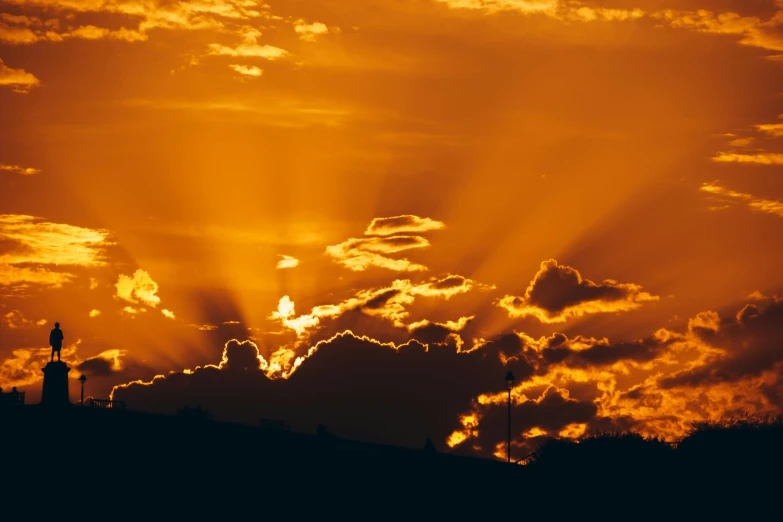 the sun sets above a church steeple with clouds