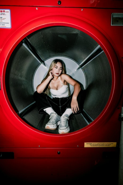 a woman sits in a washing machine and looks into the mirror