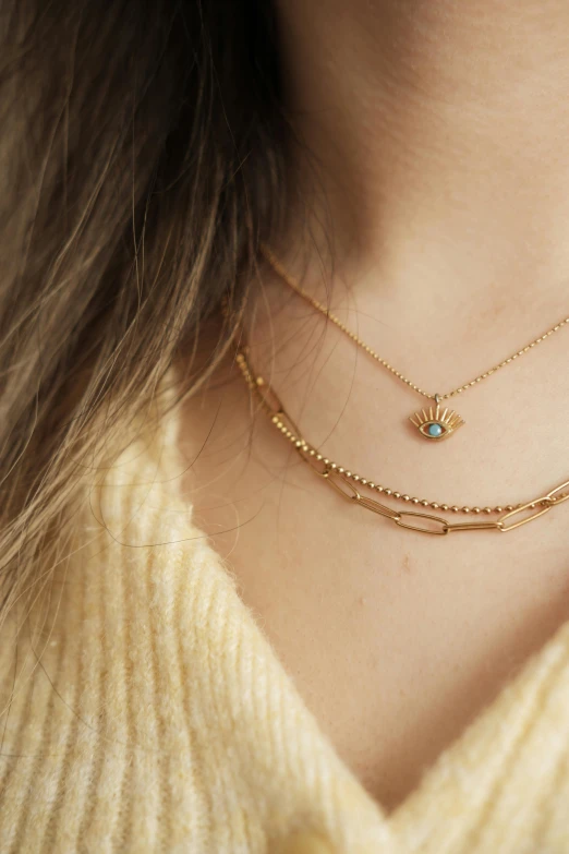 a woman wearing a gold necklace with a turquoise bead