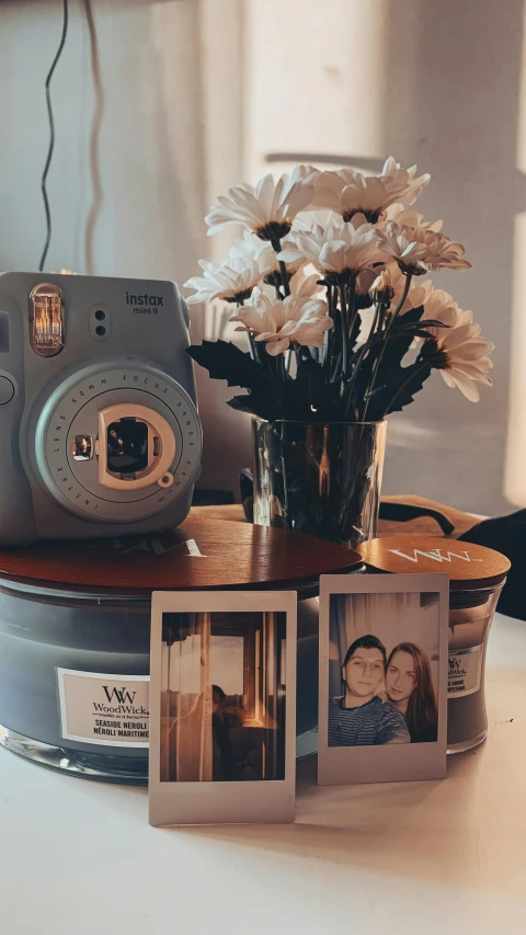 an old camera on a table with polaroid frames and flowers