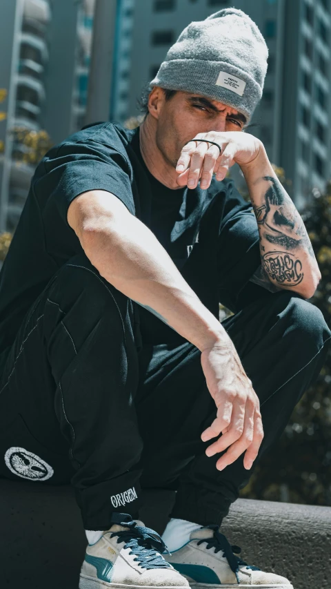 a man in black shirt and hat sitting on top of skateboard